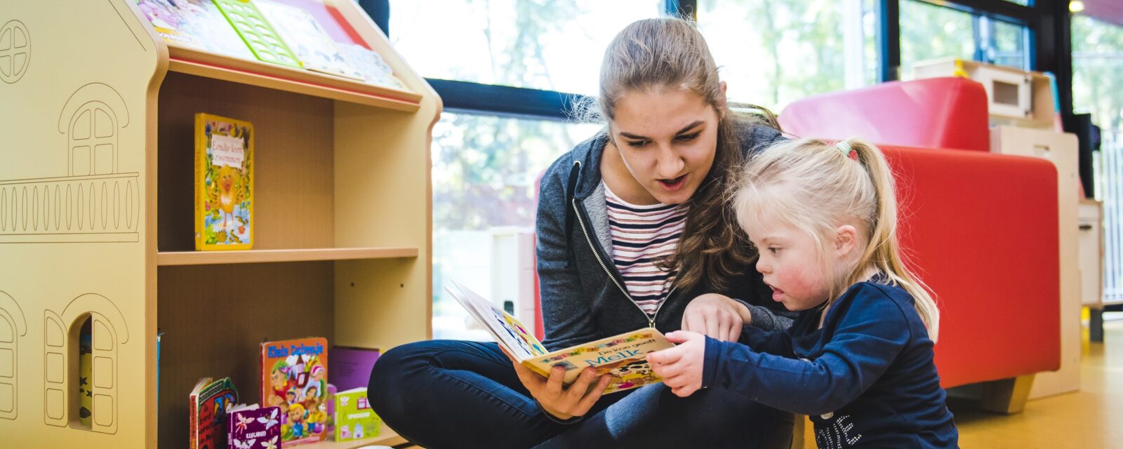 Medewerker van Adelante Kind & Jeugd lees met een kind een boekje