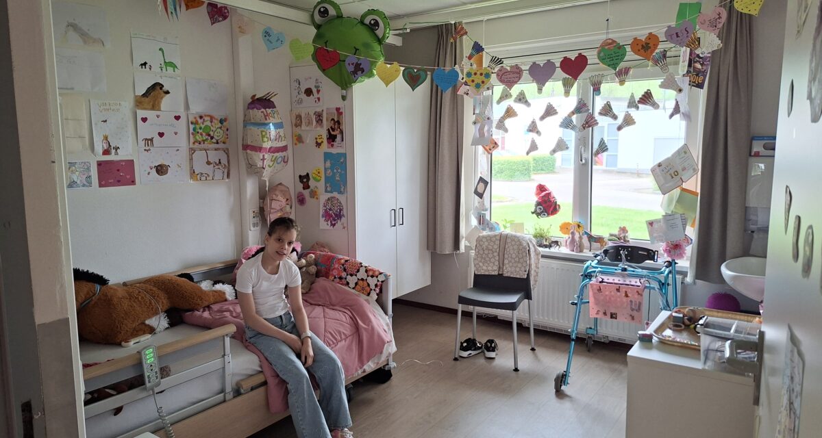 Tess zit op haar bed in haar gezellig ingerichte kamer bij Adelante.