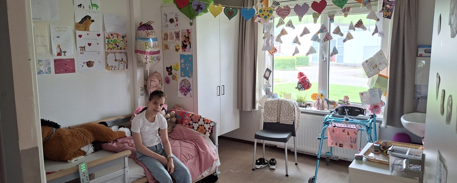 Tess zit op haar bed in haar gezellig ingerichte kamer bij Adelante.