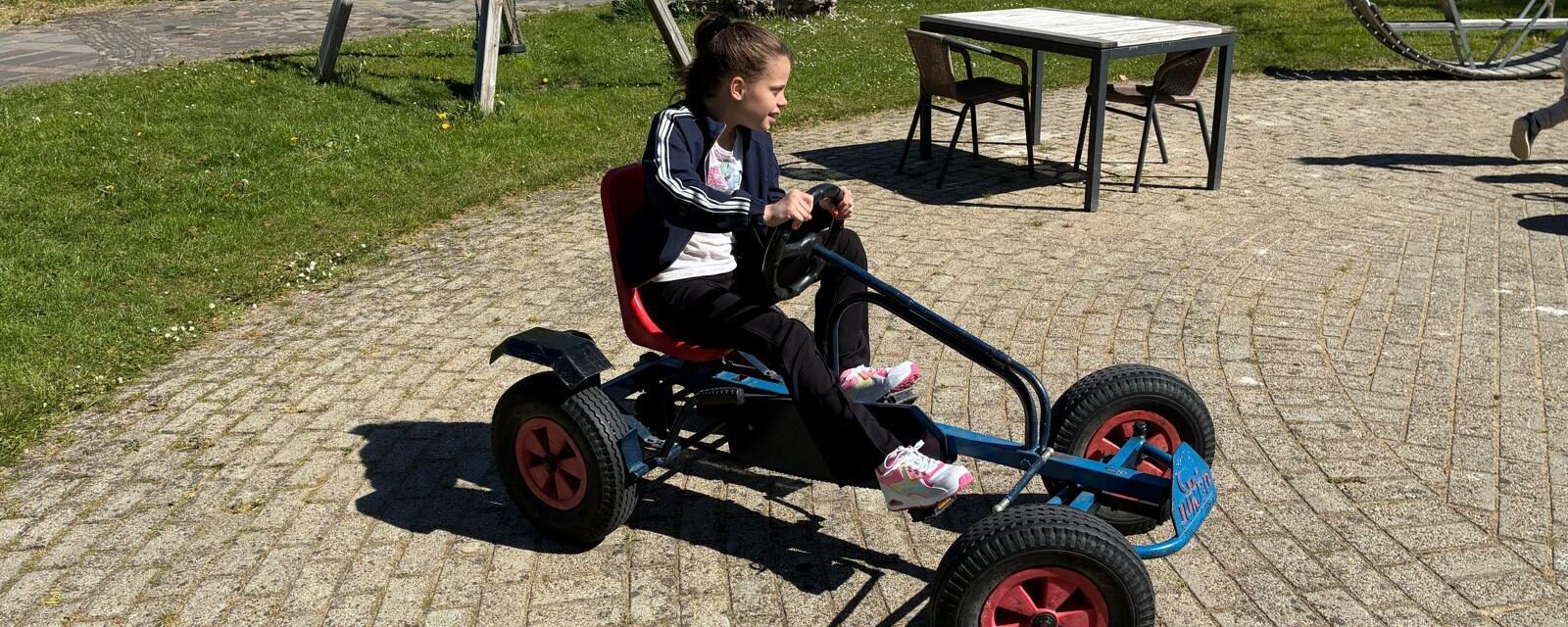 Tess is buiten en rijdt op een skelter.