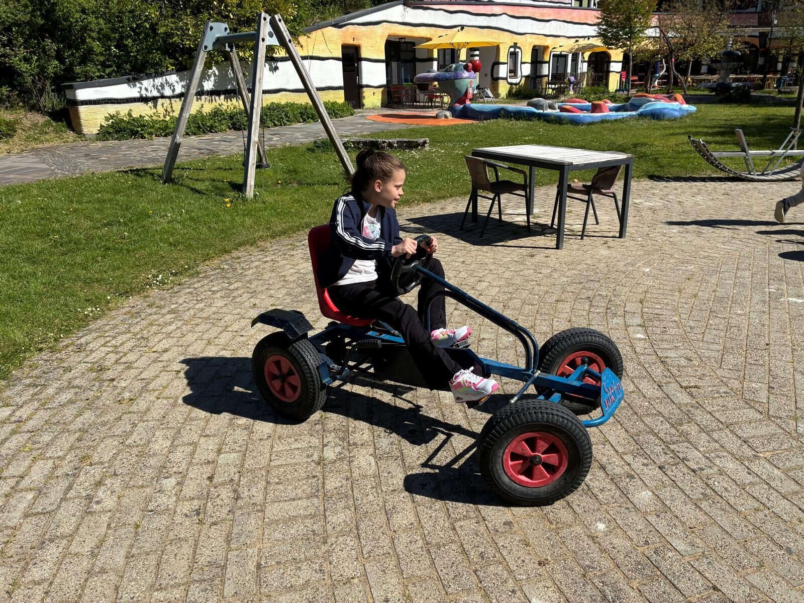 Tess is buiten en rijdt op een skelter.