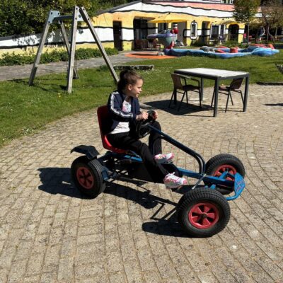 Tess is buiten en rijdt op een skelter.